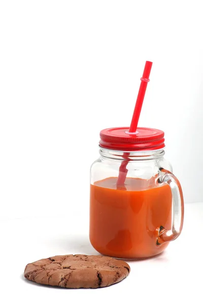 Μια κούπα χυμό καρότου και ένα μπισκότο σοκολάτας σε λευκό φόντο. Η εικόνα περιέχει κενό αντιγραφής — Φωτογραφία Αρχείου