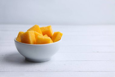 Beyaz ahşap arka planda bir kase mango succades.