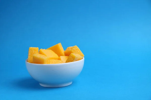 Tazón blanco de sucesiones de mango aislado sobre fondo azul — Foto de Stock