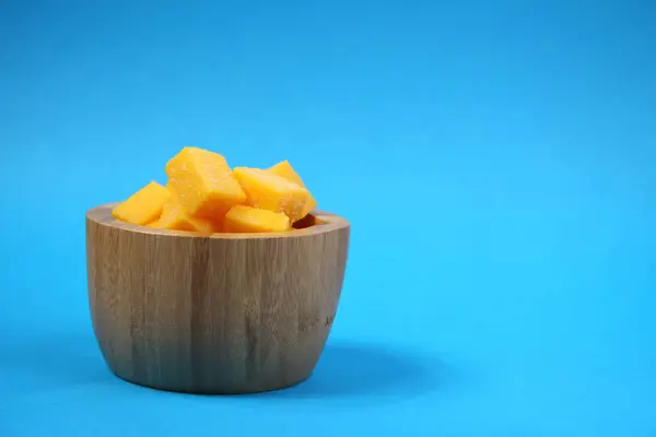 Hölzerne Schüssel Mango gelingt isoliert auf blauem Hintergrund — Stockfoto