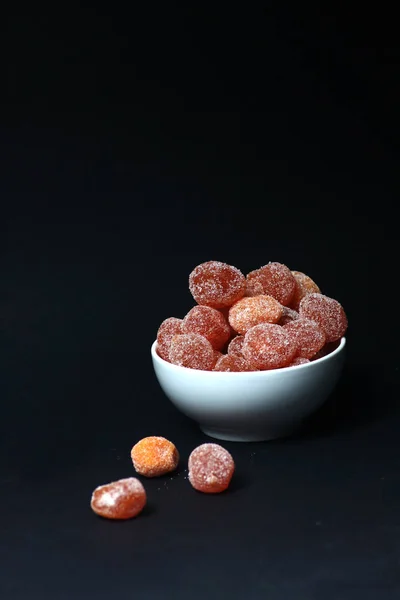 A bowl of kumquat coated with sugar isolated on black background. Vertical image — Stock Photo, Image