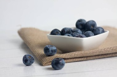 Bir kase yaban mersini ve ahşap masa üzerinde peçete.