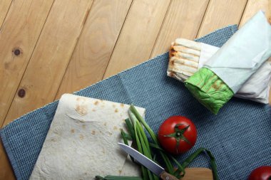 İki donör kebap, lavaş ve domates ve ahşap arka planda düz bir zemin. Resim kopyalama alanı içeriyor