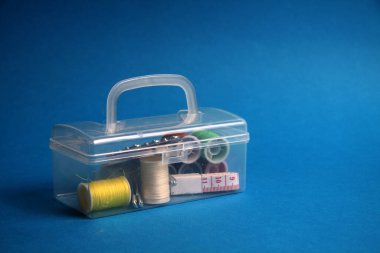 Mavi arka planda dikiş seti olan plastik kutu. Resim kopyalama alanı içeriyor