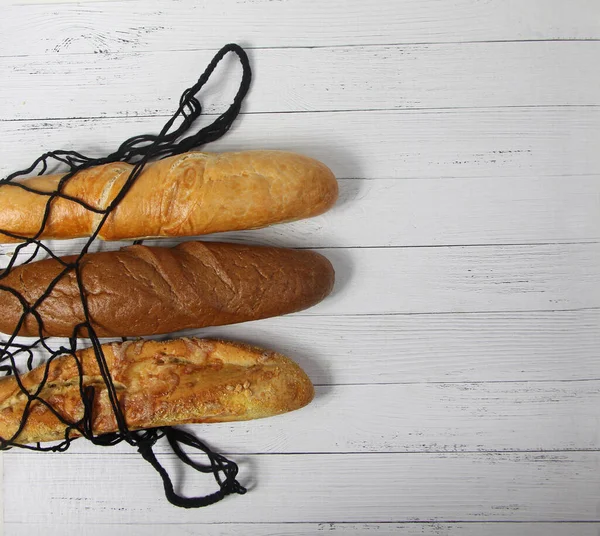 Drei Baguettes Einer Saitentüte Isoliert Auf Weißem Holzgrund Flach Lagen — Stockfoto