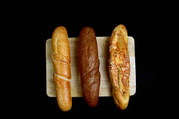 Drei Baguettes Auf Einem Hölzernen Schneidebrett Auf Schwarzem Hintergrund Lagen — Stockfoto