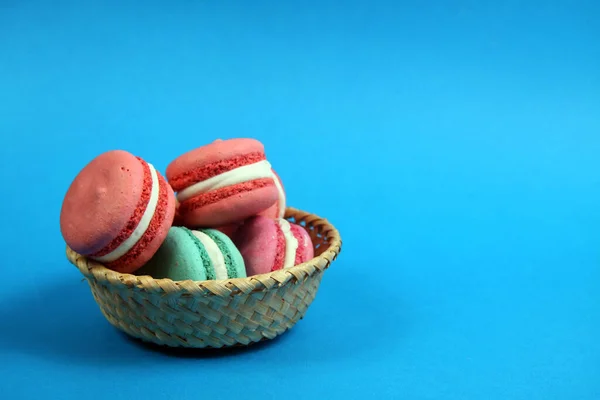 Macarons Van Verschillende Kleuren Een Mandje Blauwe Achtergrond Plat Gelegd — Stockfoto