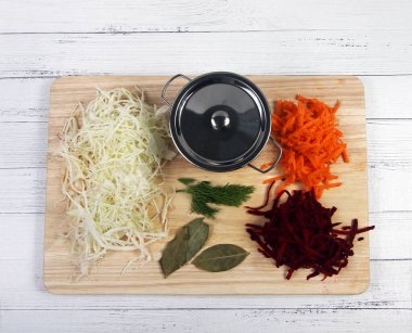 Ahşap arka planda tahta üzerinde sebze karışımı ve pişirme kabı düz yatıyordu. Yemek pişirme konsepti. Resim kopyalama alanı içeriyor