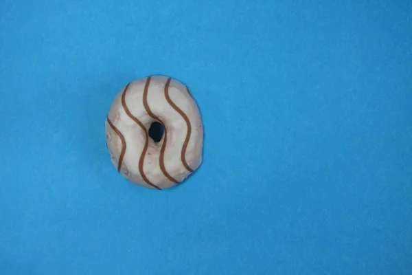 Mavi arka planda izole edilmiş çikolatayla süslenmiş donut. Resim kopyalama alanı içeriyor