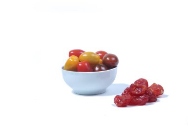 Bir kase vişneli domates ve beyaz arka planda izole edilmiş bir yığın kurutulmuş domates. Yatay görüntü. Resim kopyalama alanı içeriyor