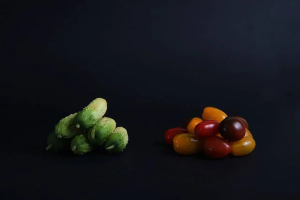 Ein Haufen Gurken Und Ein Haufen Kirschtomaten Isoliert Auf Schwarzem — Stockfoto