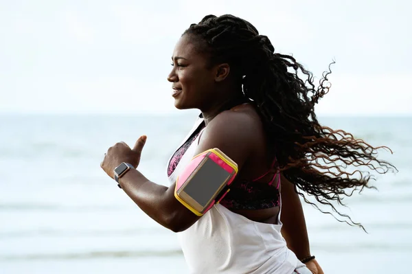 Female african runner jogging during outdoor workout on beach un