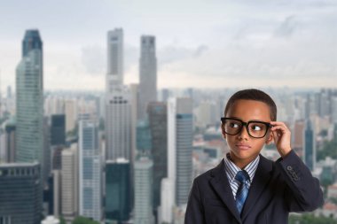 Liderlik ve başarı kavramı. Singapur şehrinin arka planında gözlük takan düşünceli Afro-Amerikan çocuk..