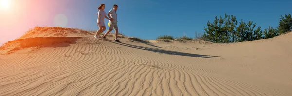 pair of young people walking along the sand dunes. Spring season, April. Web banner. Ukraine. Europe.