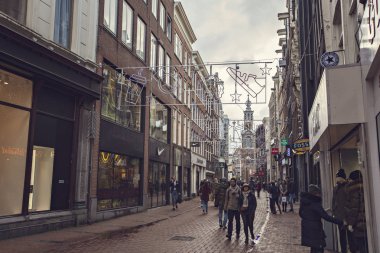 AMSTERDAM, NETHERLANDS - Aralık 2019: Hollanda 'nın başkenti Amsterdam' da dükkanları ve insanları olan turistik cadde