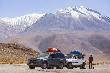 Kar kaplı volkanın önündeki kamyonlar, Bolivya Altiplano, Bolivya 'nın güzel manzarası. 
