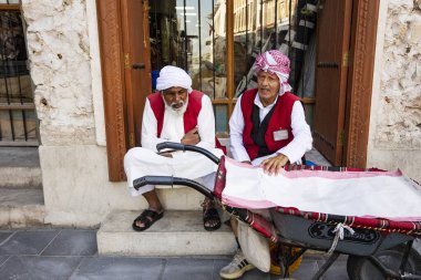 Geleneksel kıyafetler giyen Arap erkekler pazarda birbirleriyle konuşuyorlar Souq Waqif, Doha, Katar
