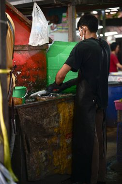 Thai man selling fish on the Maeklong Railway Market, Bangkok, Thailand