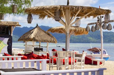 GILI HAVA, INDONESIA - Şubat 2020: Gili Air, Bali, Endonezya 'da ahşap mobilya ve şemsiyeli konforlu plaj kafesi