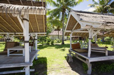 Gili Air, Bali, Endonezya 'da ahşap mobilyaları ve şemsiyeleri olan rahat bir plaj salonu.