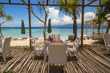 Gili Air, Bali, Endonezya 'da ahşap mobilyaları ve şemsiyeleri olan rahat bir plaj salonu.