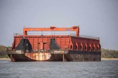 Yaşlı yıpranmış kırmızı ve siyah mavna nehir kenarına demirlemiş.