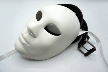 Tiyatro ya da kadın düşmanı konsepti. Beyaz klasik tiyatro maskesine yakın çekim ve erkekler cinsel istismar veya erkeklik sembolü olarak eşyalar giyiyorlar..