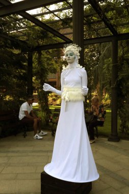 Timisoara, Romania- 09.06.2019 Living statue of a Goddess of the winter or ice. Woman dressed in a white dress pose as a realistic human statue wearing a snowball hat. clipart
