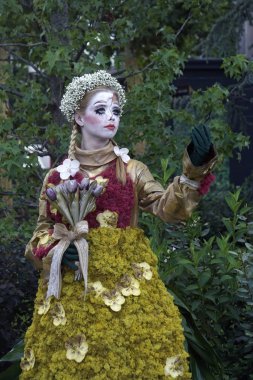 Timisoara, Romanya- 09.06.2019 Doğa Tanrıçası Flora. Çiçek takmış ve elinde buket olan kostümlü bir kadın gerçekçi bir insan heykeli gibi duruyor..
