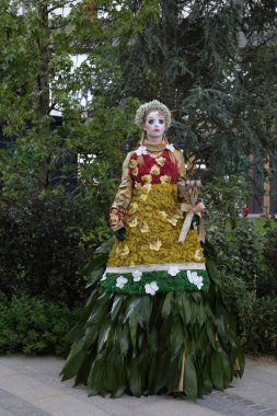 Timisoara, Romanya- 09.06.2019 Doğa Tanrıçası Flora. Çiçek takmış ve elinde buket olan kostümlü bir kadın gerçekçi bir insan heykeli gibi duruyor..