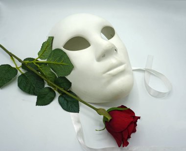 Tiyatro ya da aşk konsepti. Beyaz klasik tiyatro maskesi ve kırmızı gül cinsel özgürlüğün sembolü..