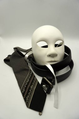 Tiyatro ya da kadın düşmanı konsepti. Beyaz klasik tiyatro maskesine yakın çekim ve erkekler cinsel istismar veya erkeklik sembolü olarak eşyalar giyiyorlar..