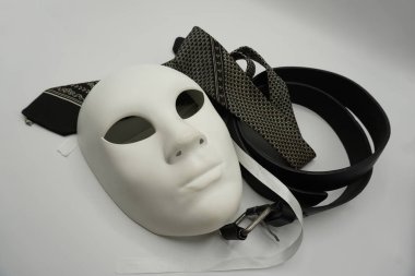 Tiyatro ya da kadın düşmanı konsepti. Beyaz klasik tiyatro maskesine yakın çekim ve erkekler cinsel istismar veya erkeklik sembolü olarak eşyalar giyiyorlar..