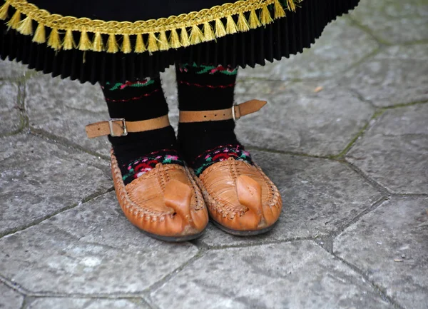 Táncosok lábai egy tradicionális román táncban, tradicionális szép jelmezben és paraszti szandálban, bőrből.. — Stock Fotó