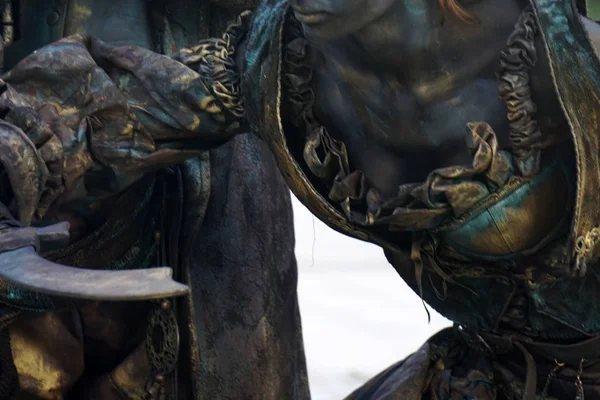 Details of Living statue of two pirates. Woman and man dressed in bronze costumes with hats and weapons pose as a realistic human statue. — Stock Photo, Image