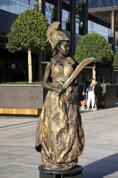 Timisoara, Romania- 09.06.2019 Living statue of Pallas Athena. Woman dressed in bronze dress wearing a helmet and a spear poses as a realistic human statue. — Stock Photo, Image