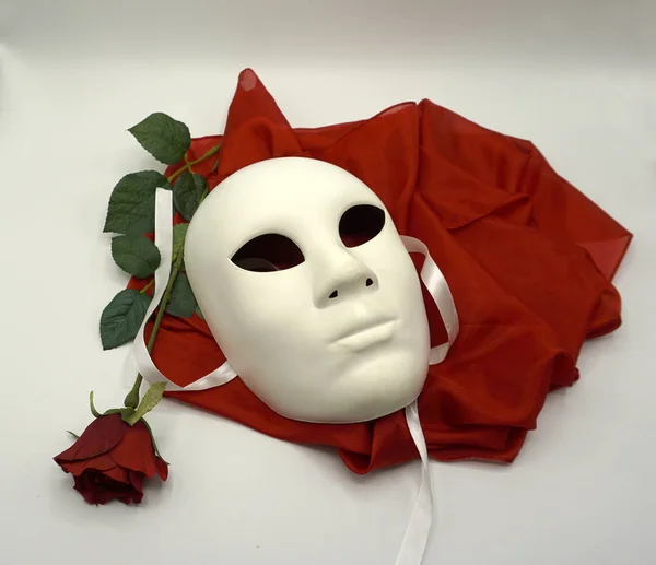 Koncepcja teatralna lub romantyczna. Zbliżenie białej klasycznej maski teatralnej i czerwonej róży jako symbolu wolności seksualnej. — Zdjęcie stockowe