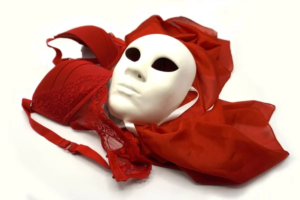 Koncepcja teatralna lub romantyczna. Zbliżenie białej klasycznej maski teatralnej i czerwonej bielizny jako symbolu wolności seksualnej. — Zdjęcie stockowe