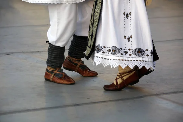 Dansare fötter i en traditionell rumänsk dans bär traditionella vackra kostymer och bonde sandlas gjord av läder. Royaltyfria Stockfoton