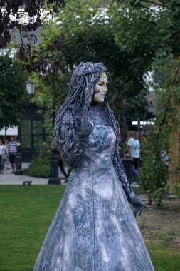 Timisoara, Romanya- 09.06.2019 Orman Tanrıçasının Yaşayan Heykeli. Gümüş elbiseli kadın gerçekçi bir insan heykeli gibi poz veriyor..