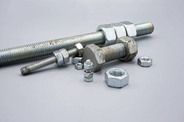 Metal screws and nuts isolated on gray background. New and shiny chrome screws and nuts. Copy space.