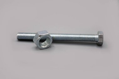 Metal screws and nuts isolated on gray background. New and shiny chrome screws and nuts. Copy space.