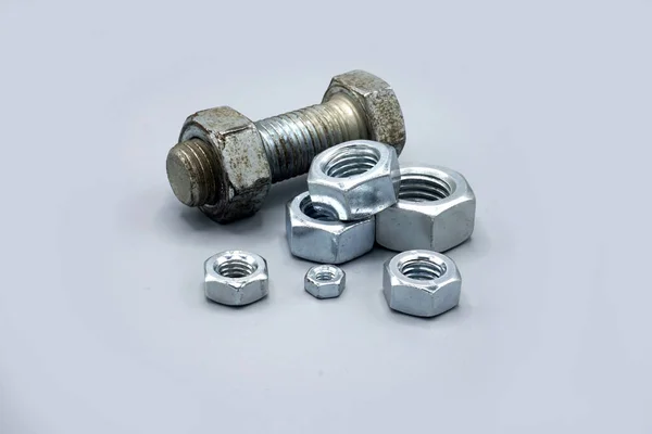 Metal screws and nuts isolated on gray background. New and shiny chrome screws and nuts. Copy space. — Stok fotoğraf