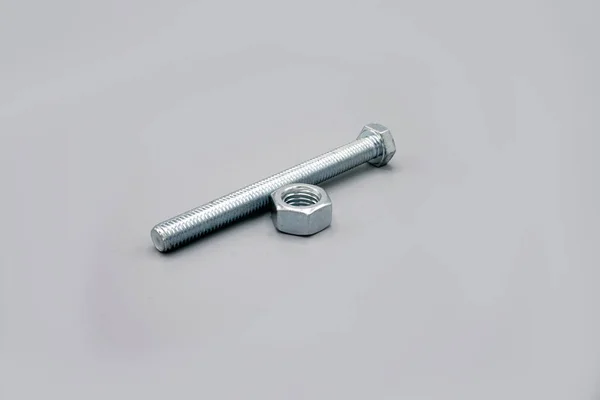 Metal screws and nuts isolated on gray background. New and shiny chrome screws and nuts. Copy space. — 图库照片