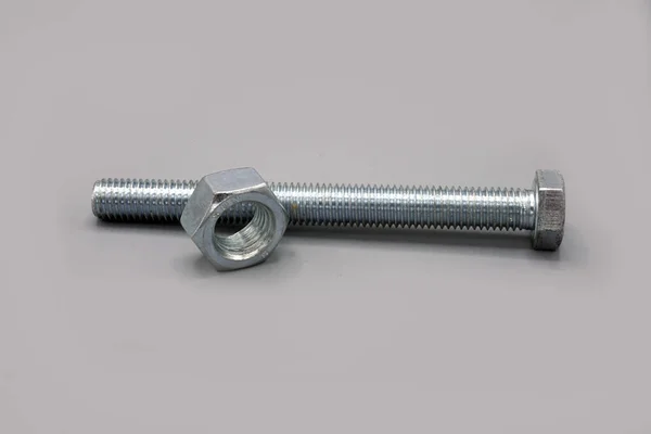 Metal screws and nuts isolated on gray background. New and shiny chrome screws and nuts. Copy space. — ストック写真