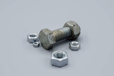Metal screws and nuts isolated on gray background. New and shiny chrome screws and nuts. Copy space.