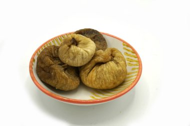 Beyaz arka planda izole edilmiş seramik bir tabakta kurumuş incir. Enerji ve fiber doğal kaynak.
