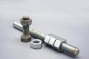 Stainless steel screws and nuts isolated on gray background. New and shiny chrome screws and nuts. Copy space.
