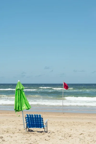 Зеленый зонтик синий стул и красный флаг — стоковое фото
