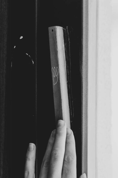 A black and white photo of a man touching a mezuzah